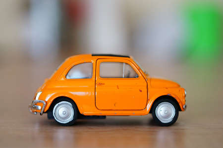 POZNAN, POLAND - Jan 14, 2020: Welly small orange vintage toy model car on a wooden table in soft...
