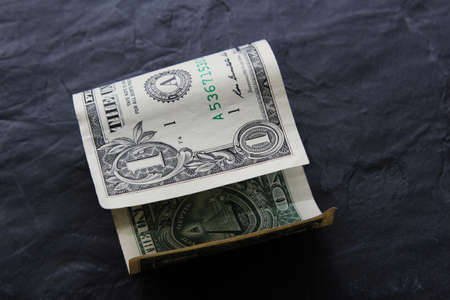 A high angle closeup shot of a dollar bill on a black surfaceの写真素材
