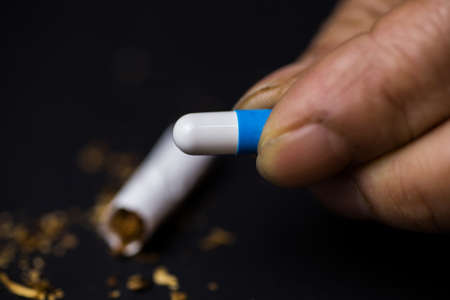 A closeup  shot of a person holding a medicine capsule in front of a black backgroundの写真素材