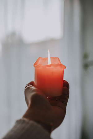 A closeup shot of a hand tightly holding a lit up candleの写真素材