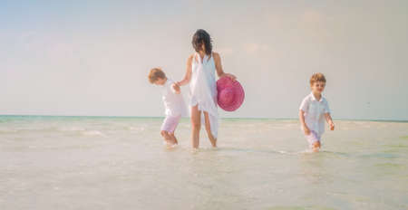 A cheerful mother playing with her two children on the beach during daytime