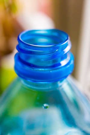 A vertical closeup shot of an opened plastic bottle with a blurred background