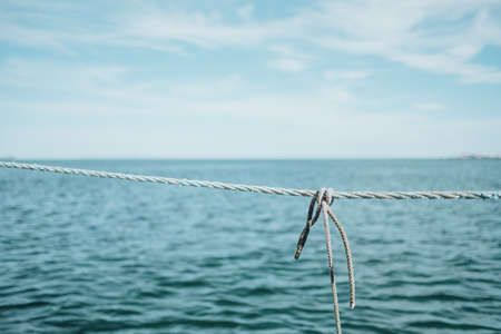 A closeup shot of a gray rope near the ocean under a cloudy sky during daytime