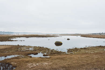 A wide angle shot of a dry landscape full of water under a cloudy sky