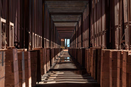 A long corridor in the industrial building with shadows of the columns on the groundの写真素材