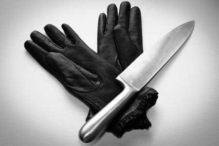 An overhead shot of a metal knife over black gloves on a  white surfaceの写真素材