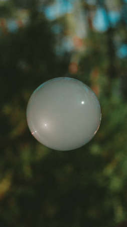 A vertical shot of a white ball with a blurred natural backgroundの写真素材