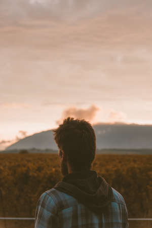 A vertical shot of a lonely person enjoying the beautiful view of the sunsetの写真素材