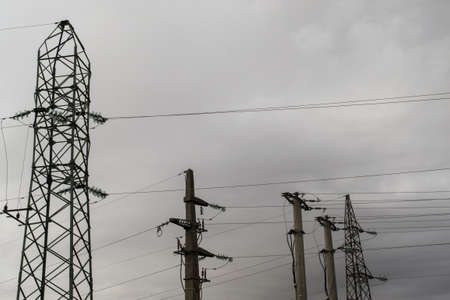 A low angle shot of electric posts and line against a cloudy sky