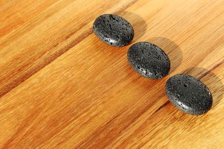 A wooden surface with black lava beads in a spa salon - great for background or wallpaperの写真素材