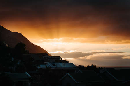 A silhouette shot of houses with a sunrise in the backgroundの写真素材