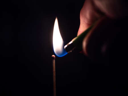 A selective focus shot of a person lighting up a match stick in the darknessの写真素材
