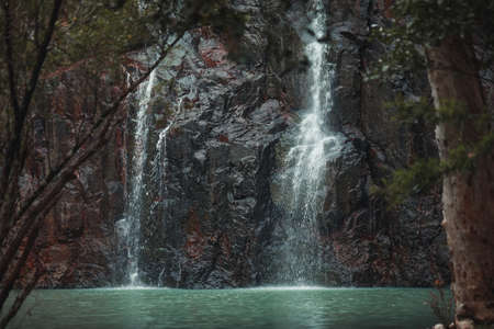 A closeup shot of a waterfall in the woods surrounded by treesの写真素材