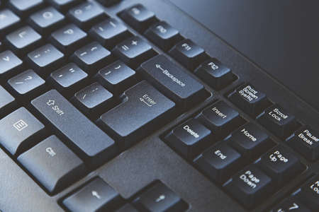 A high angle closeup shot of a black computer keyboard on a black surface