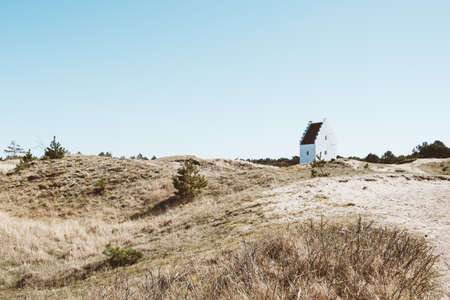 A wide angle shot of a white house on a dry landscape under a blue skyの写真素材