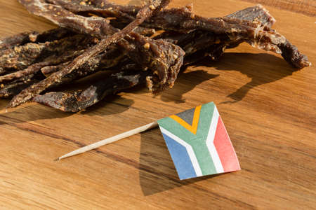 The flag of South Africa on traditional biltong snack on a wooden surface