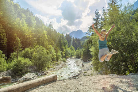 A female happily jumping in a beautiful landscape of the Triglav National Park in Sloveniaの写真素材