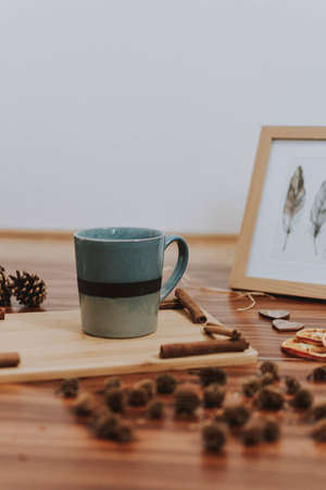 A cup put on a brown patterned table around other objects next to a picture of feathersの写真素材