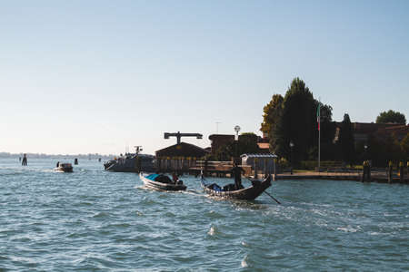 A beautiful shot of boats on the water near the shore at Venice Italy Canals