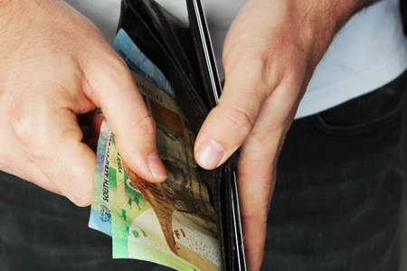 A high angle closeup shot of a person putting some cash in a leather wallet