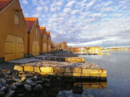 A scenery of buildings around the lake under the cloudy sky in Stavern Norwayの写真素材