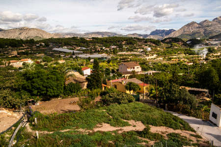 A bird's eye view of the lush nature and old buildings with beautiful mountains in Polop, Spainの写真素材