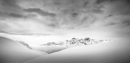 A panoramic shot of snowy mountain tops under a dark cloudsの写真素材