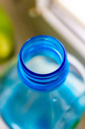 A vertical closeup shot of an opened plastic bottle with a blurred backgroundの写真素材