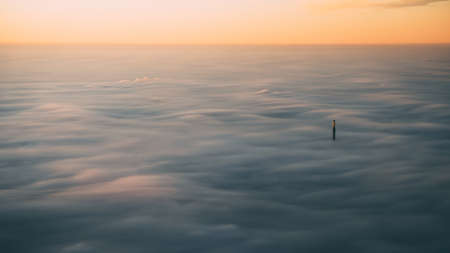 A beautiful scenery over the clouds with the breathtaking view of sunset in the backgroundの写真素材