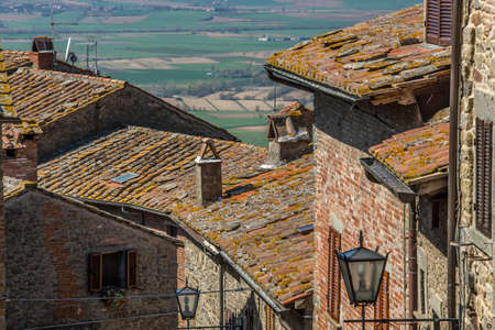 A high angle shot of the roofs of the village houses with the valley in the background