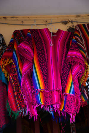 A vertical low angle shot of handmade colorful clothes hung in a marketの写真素材