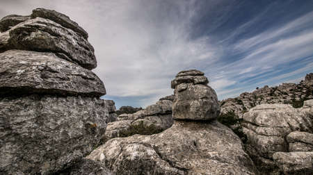 A closeup shot of several grey rocks on top of each other under a cloudy skyの写真素材