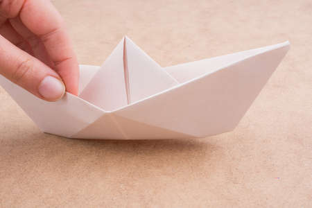 A closeup shot of white a paper ship on a wooden surfaceの写真素材