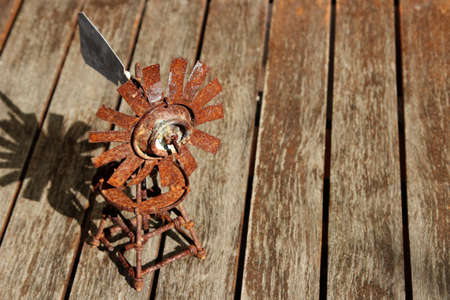 A high angle shot of a rusted small windmill on a wooden surfaceの写真素材
