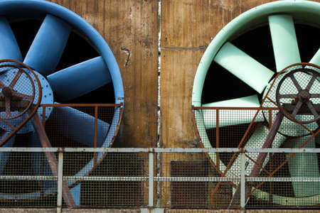 A low angle shot of two huge white and blue fans on a stone buildingの写真素材