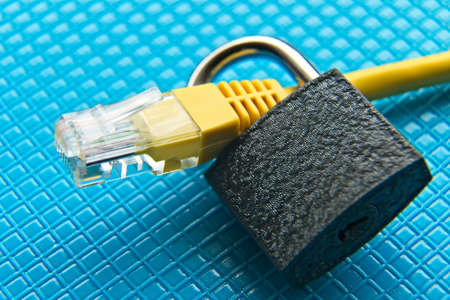 A closeup shot of a yellow cable and a lock around it on a blue surfaceの写真素材