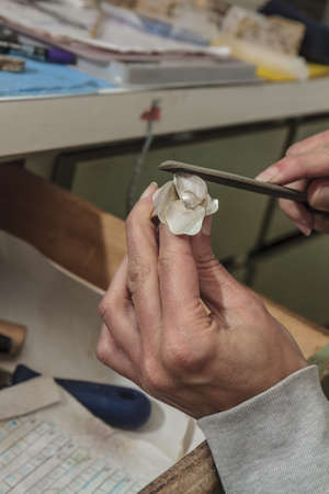 A closeup shot of an artisan carving and grinding a piece of jewelry