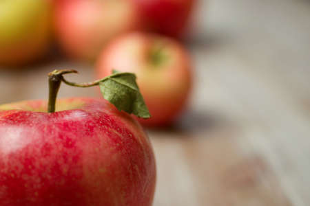 A closeup shot of a red apple with a stem on the top and a blurred backgroundの写真素材