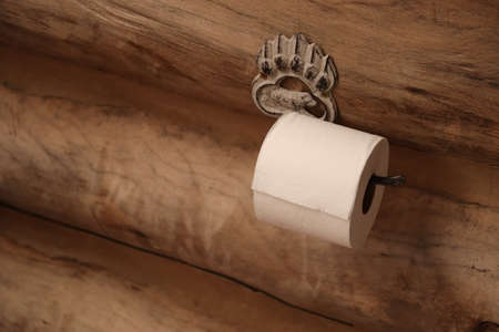 A closeup shot of a white toilet paper on a wooden wall in a bathroomの写真素材