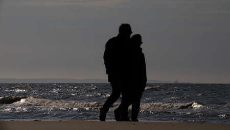 A silhouette of a couple walking on the seashore