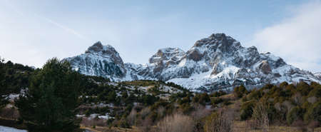 A beautiful mountain range covered with snow under a cloudy sky in Spain
