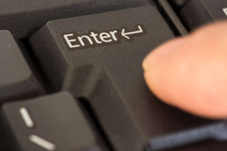 A closeup shot of a person pressing the enter button on the keyboard