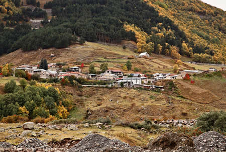 An aerial shot of a village surrounded by mountains during autumn