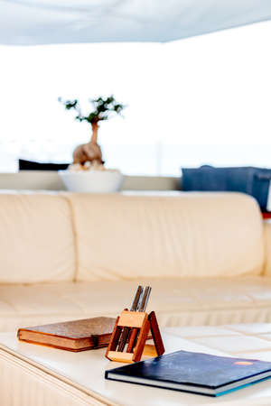 A vertical shot of pens in a wooden stand near booksの写真素材