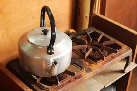 A high angle shot of an old silver kettle on a rusted stove