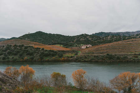 A house on a hill near the lake surrounded by high rocky mountains