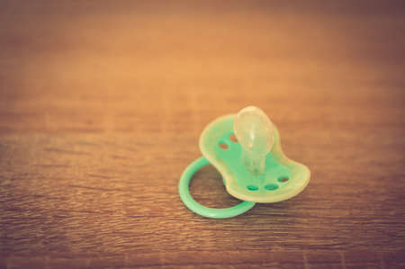 A high angle closeup shot of a green baby's dummy on a wooden surfaceの写真素材