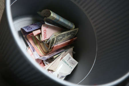 A high angle shot of a pile of cashes from different countries in a metal bucketの写真素材