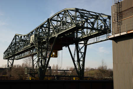 A wide shot of a huge metal structure and a building with a clear blue sky