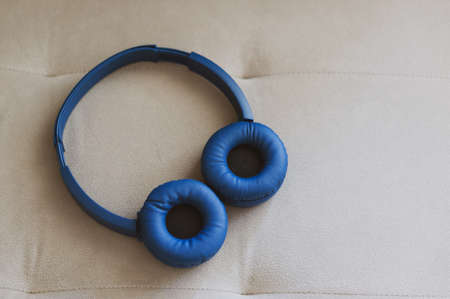 A high angle closeup shot of blue headphones on a light-colored surface